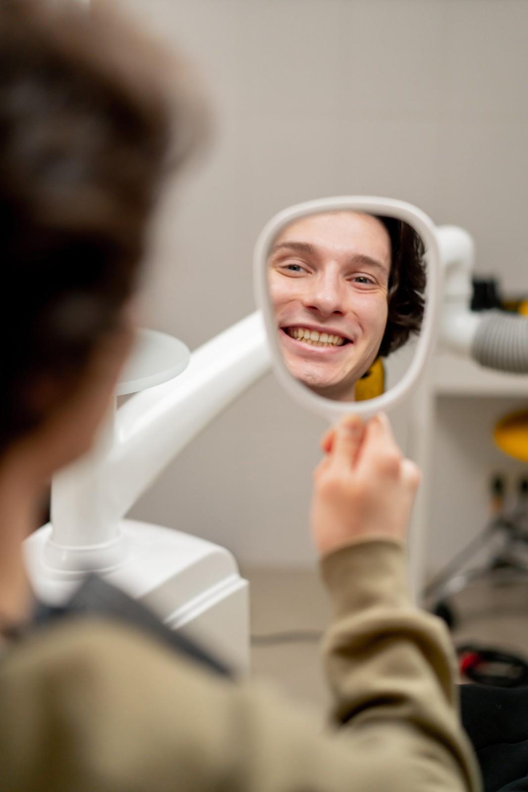 Person smiles in a dental mirror