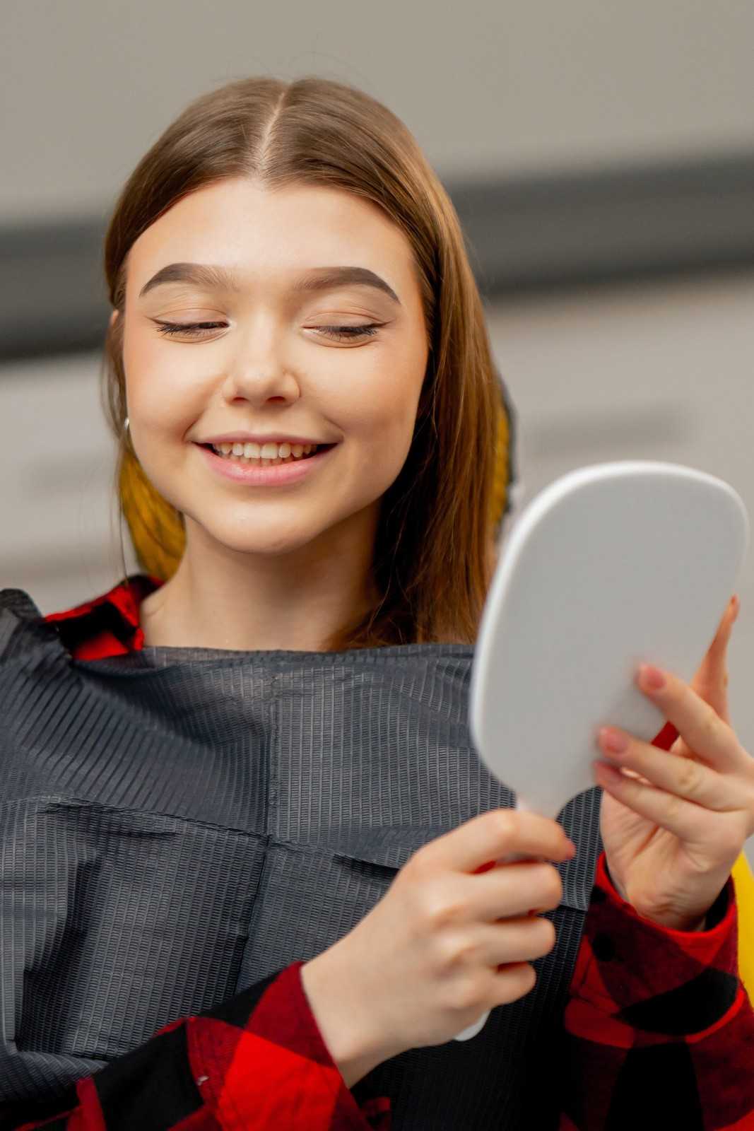 A woman is smiling while looking into a mirror