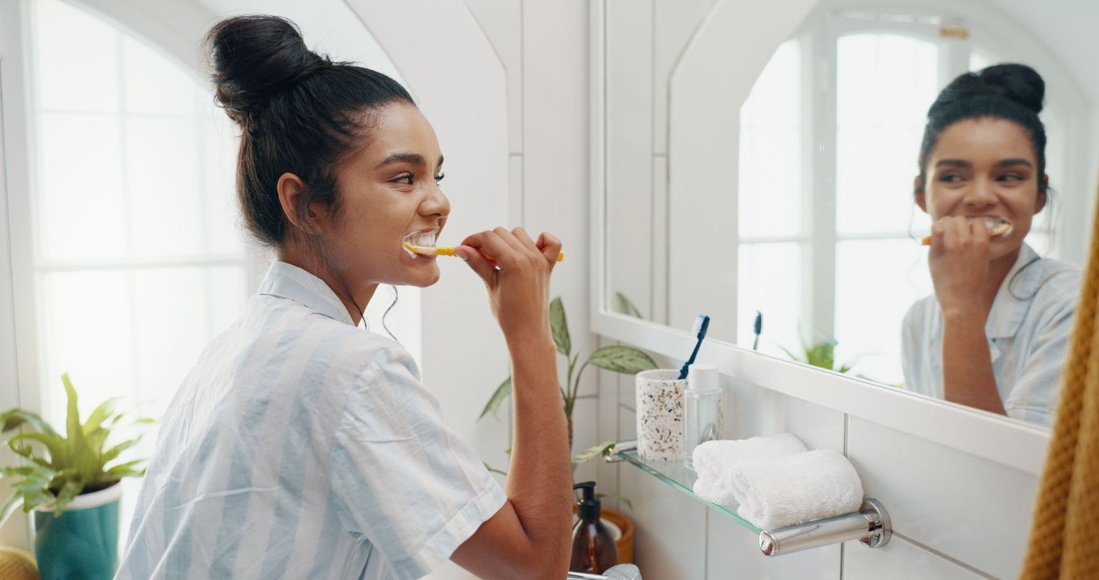 Young woman brushing teeth with fluoride toothpaste as an alternative oral care strategy if fluoride is removed from drinking water