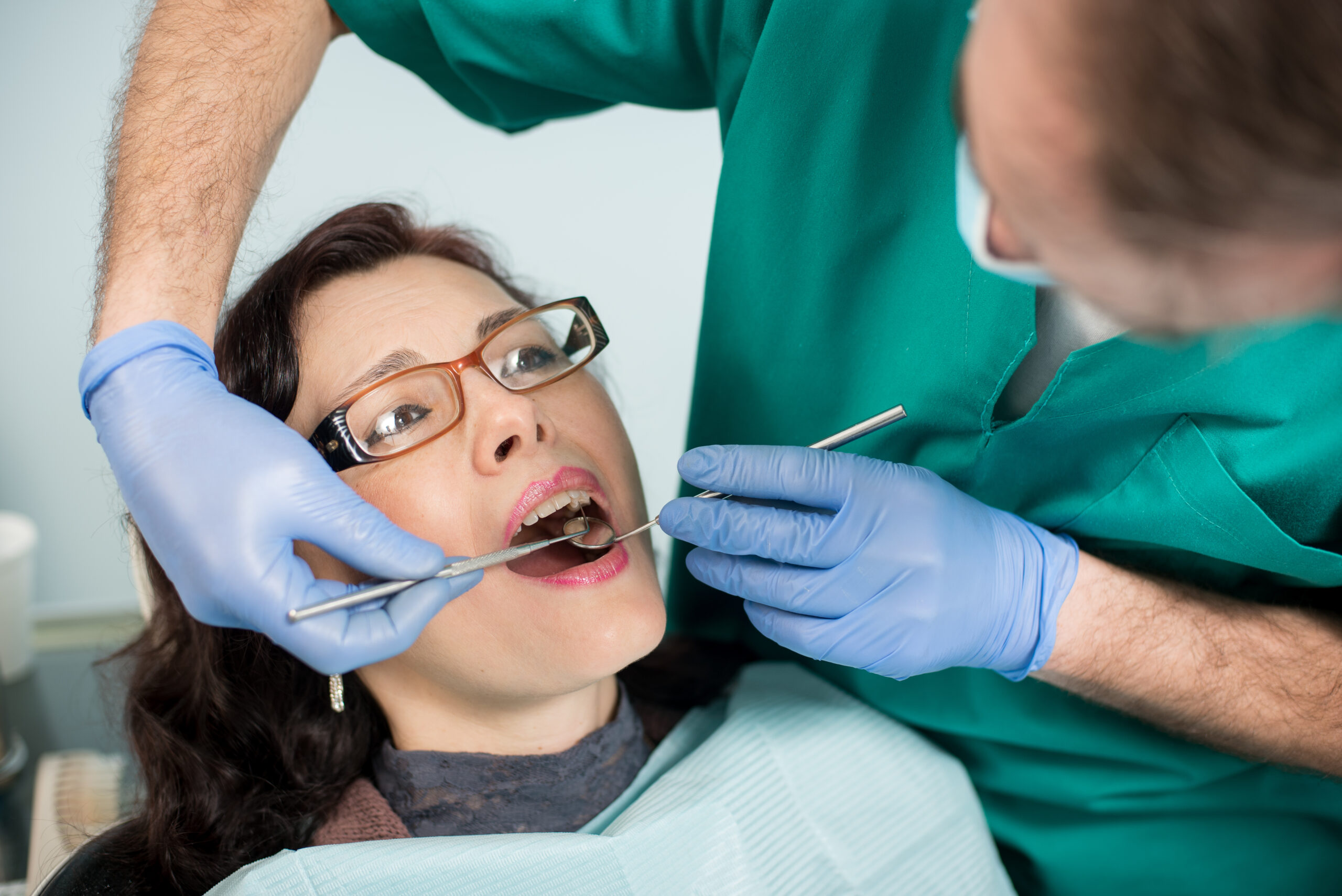 Dentist examining female patient during urgent dental care appointment in Columbia MO