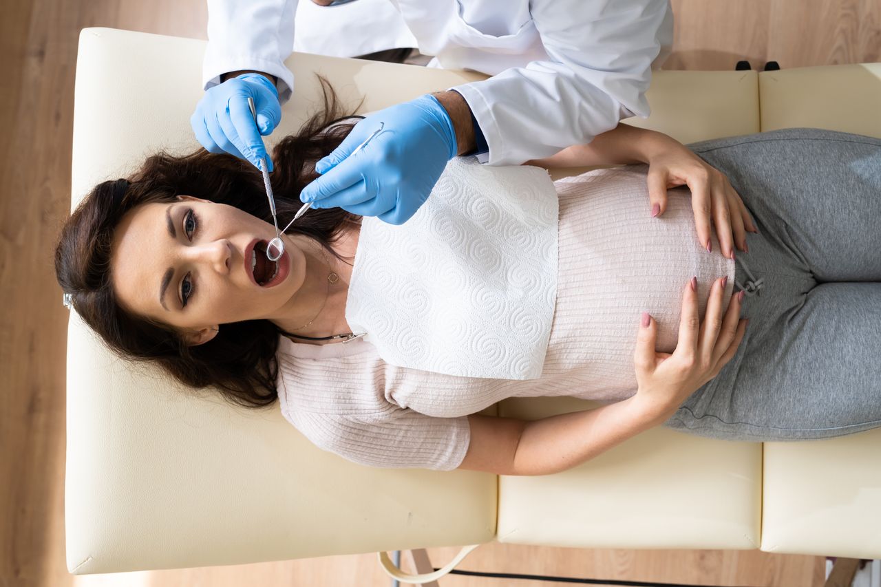 Overhead view of a pregnant woman receiving a dental checkup from a dentist, showing safe dental treatment during pregnancy