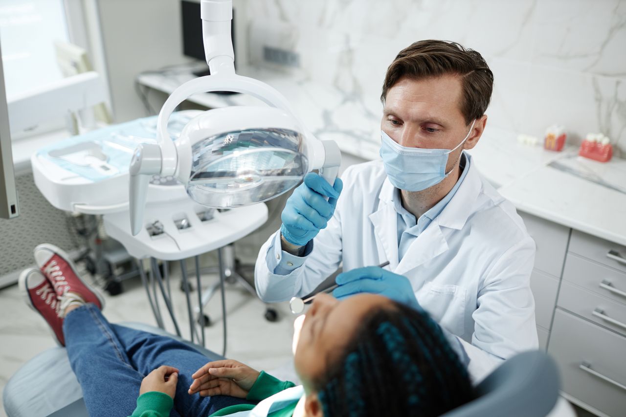 Dentist consulting with teenage patient during dental checkup